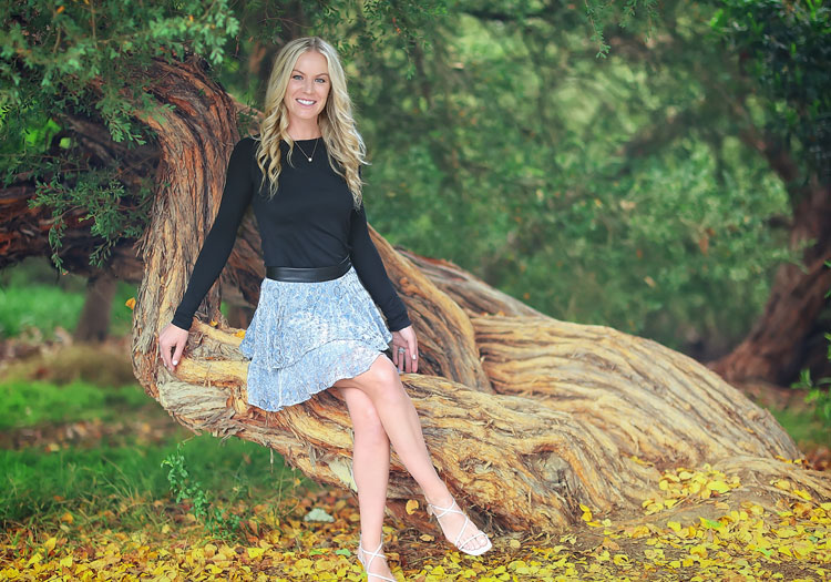 Julia Kay seated on an oak trunk among yellow leaves
